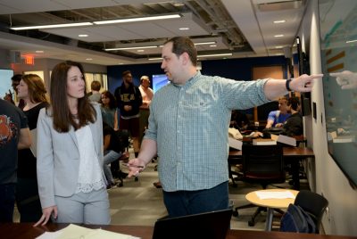 Associate professor Tabitha James listens as student Allen Fuller (right) points to a display projection during an informal Q&A session following student project presentations in her graduate class on business information visualization and analytics.