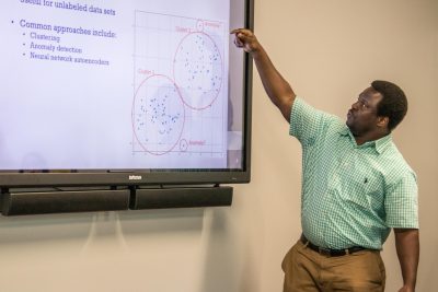 A man points to a infograph on a screen.