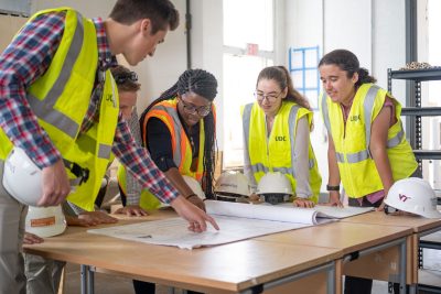 Students examine building plans at the Research + Demonstration Facility