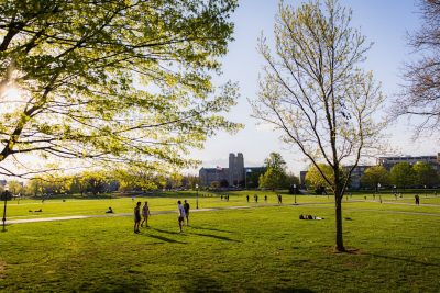 Students gather in small groups on the Drillfield with Burruss Hall in the background.