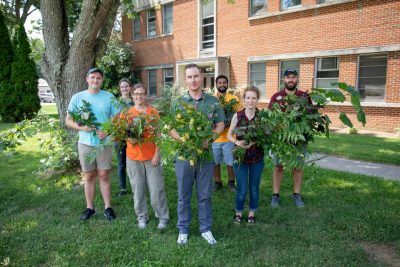 Professor Jacob Barney and six graduate students hold some of the invasive plant species they're trying to eradicate. 