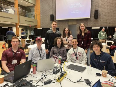 cybersecurity team gathers around a table cluttered with laptops and energy drinks at a competition 