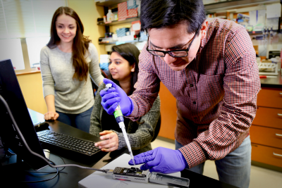 Marcela Aguilera Flores, a student in the Genetics, Bioinformatics, and Computational Biology graduate program (left), and Parul Sharma, a student in the Genetics, Bioinformatics, and Computational Biology graduate program (middle), look at the computer as Dr. Marco Enrique Mechan-Llontop, a former graduate student in the School of Plant and Environmental Sciences (right), inserts plant DNA into an Oxford Nanopore Sequencing MinIONTM device. Photo Courtesy of Alex Crookshanks for Virginia Tech.