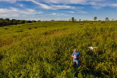 This is an image of a farmer in his fields remotely controlling a drone.